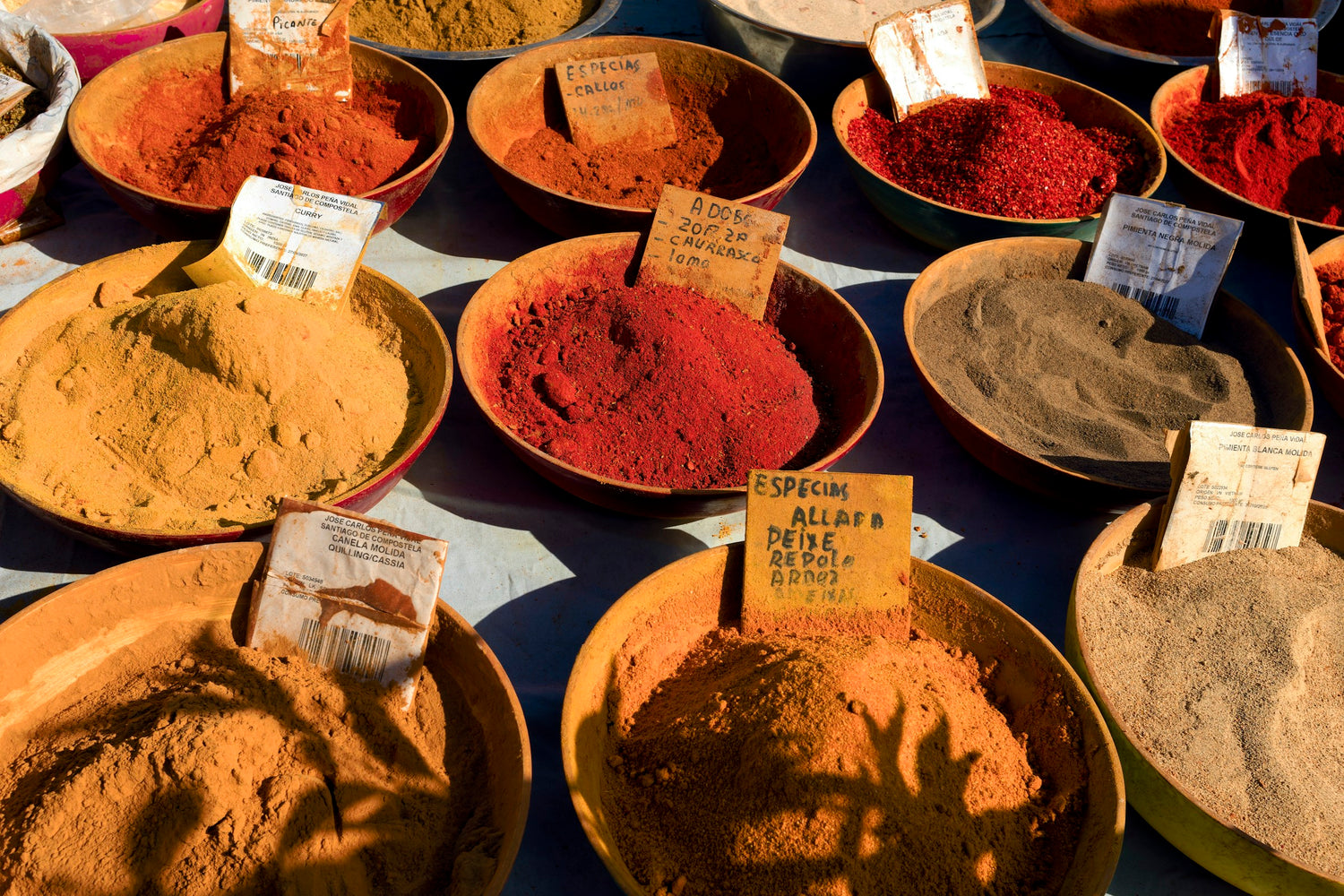 A table topped with bowls filled with different colored spices