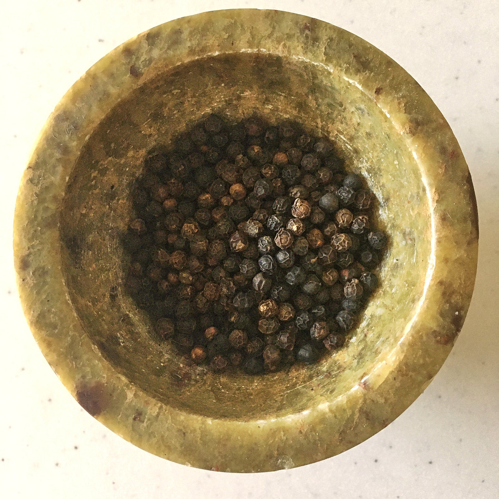 Grains de poivre noir de Madagascar dans un mortier de pierre